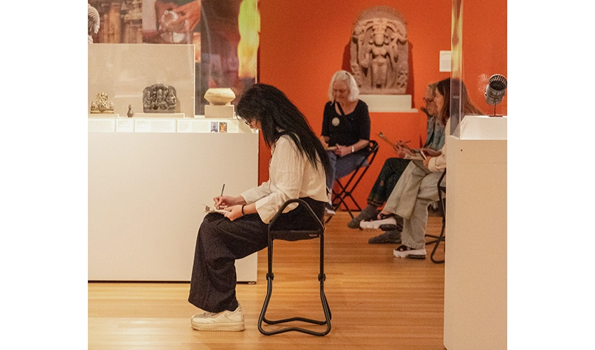 seated museum visitors sketching in the Asian gallery surrounded by art