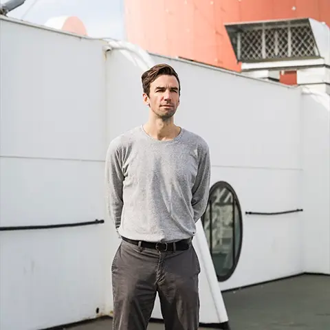 man in casual clothes aboard a ship facing the viewer 