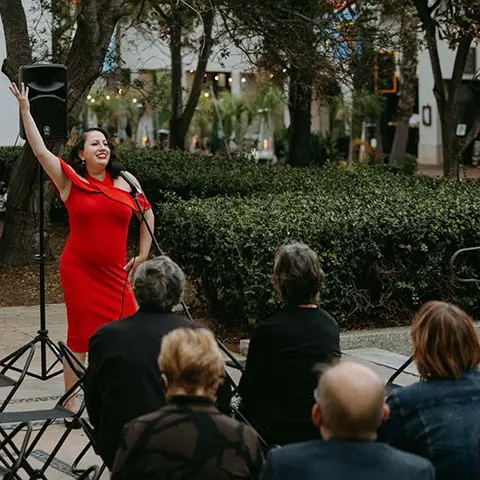 singer in a red dress posing in front of a crowd on terrace
