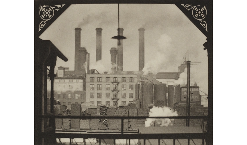 view from a decorated balcony of an industrial warehouse with smokestacks in the distance 