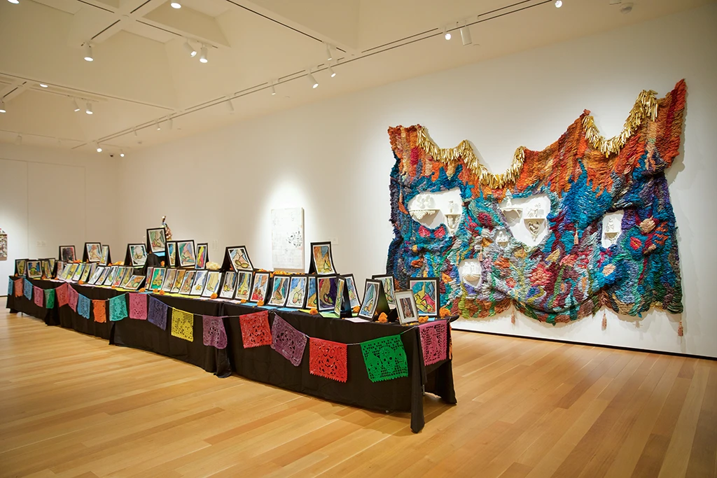 a dia de los muertos altar in a museum gallery with art on the walls