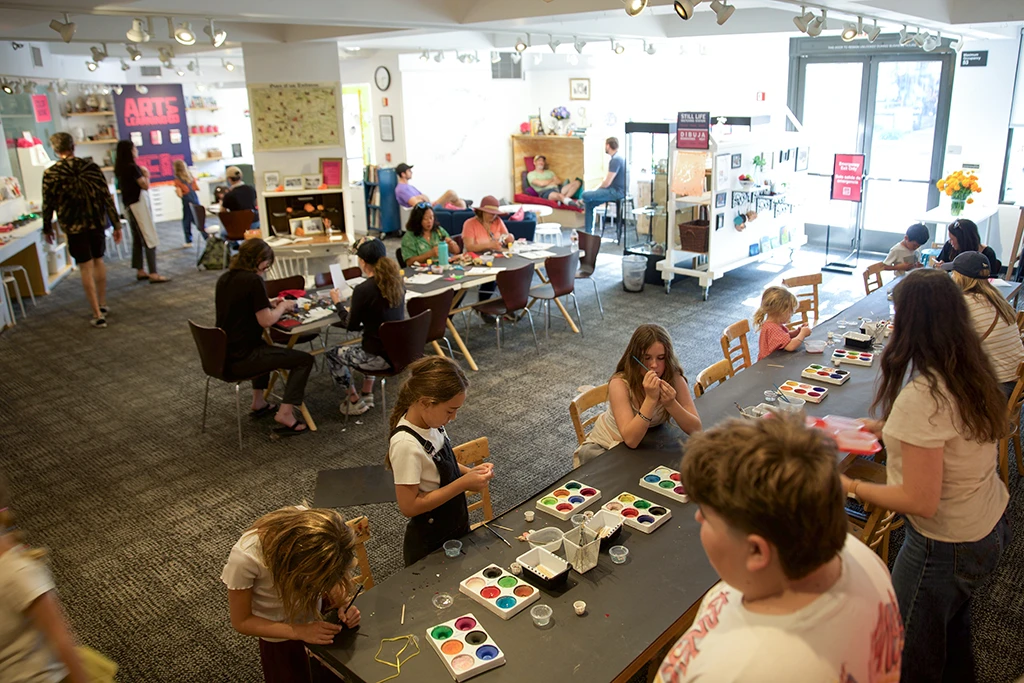 kids and adults crafting and mingling around tables in the art learning lab