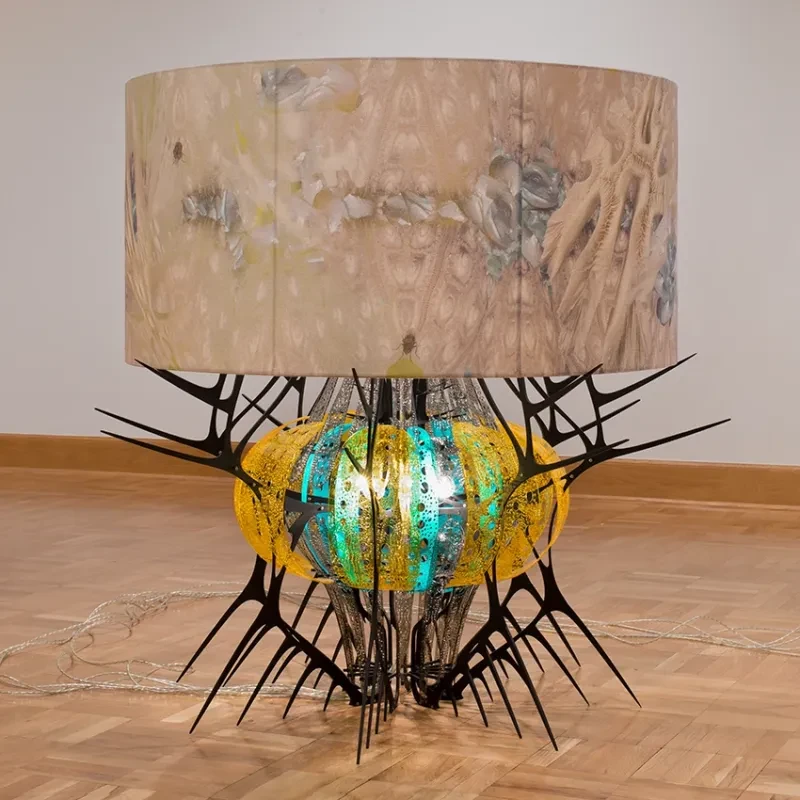 photo of a low lamp resembling a creature with yellow and green glass and spiky legs