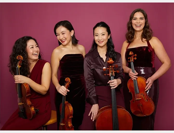 photo of quartet of string musicians holding their instruments against a maroon backdrop