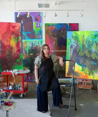 Artist Vian sora standing in front of several of her paintings