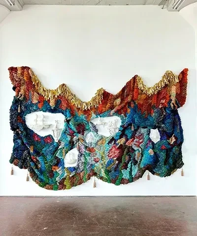 photo of colorful wall hanging surrounding sculptural objects