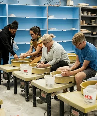 photo of adult students working with handbuilding clay led by instructor