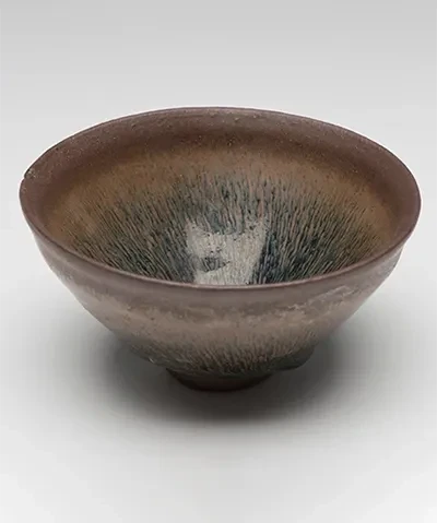 photo of a dark glazed ceramic bowl against a light gray background shot from slightly above