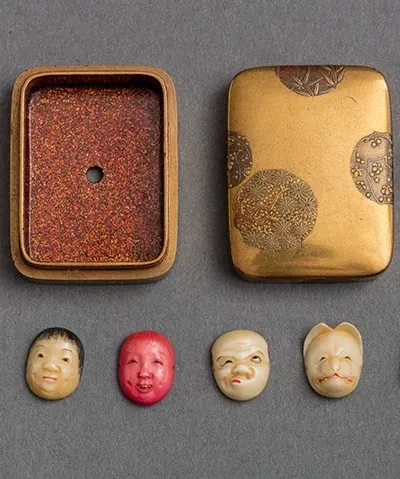 photo of four figural netsukes with open case lying flat on gray table 