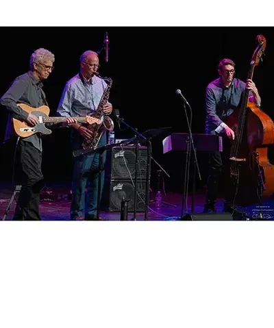 jazz trio of men including guitarist, sax player, and stand up bassist on stage playing