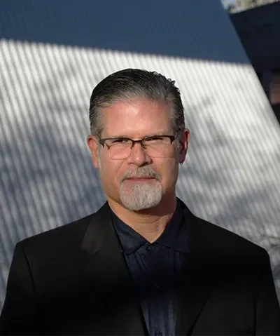 a portrait of the author roberto tejada in glasses and a dark suit
