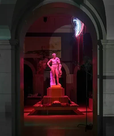 photo of statue of Hermes bathed in pink light in museum gallery