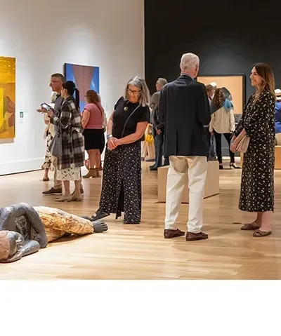 People standing in Museum galleries, talking and looking at art.