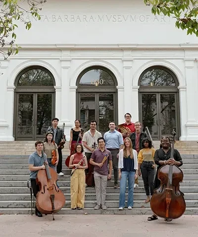 group of young people with their instruments standing on the front steps of the museum entrance