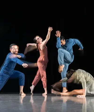 photo of dancers posing in jumpsuits against a dark backdrop