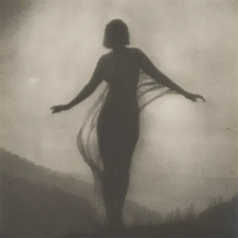 black and white photo featuring a silhouette of a figure, presumably a woman, with their arms raised slightly standing outdoors