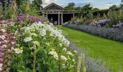 Photo of garden with flowers in foreground and ancient looking structure in the background