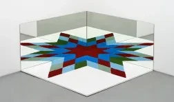 photo of work against a corner of a room featuring a star rendered from a mirrored image of multi colored material
