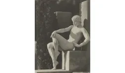 a seated nude man painted white and strategically posed resembling a marble statue